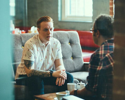 Tristan Manco, Illustration lecturer and Jake Williams, graduate, sit in a cafe chatting