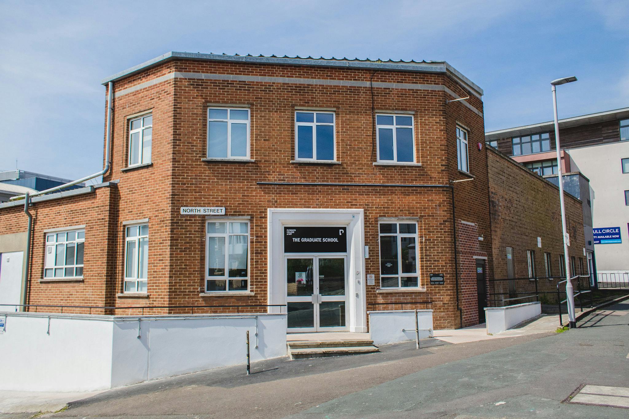 A red-brick corner building with two floors, central double doors and sash windows is home to our postgraduate studios.