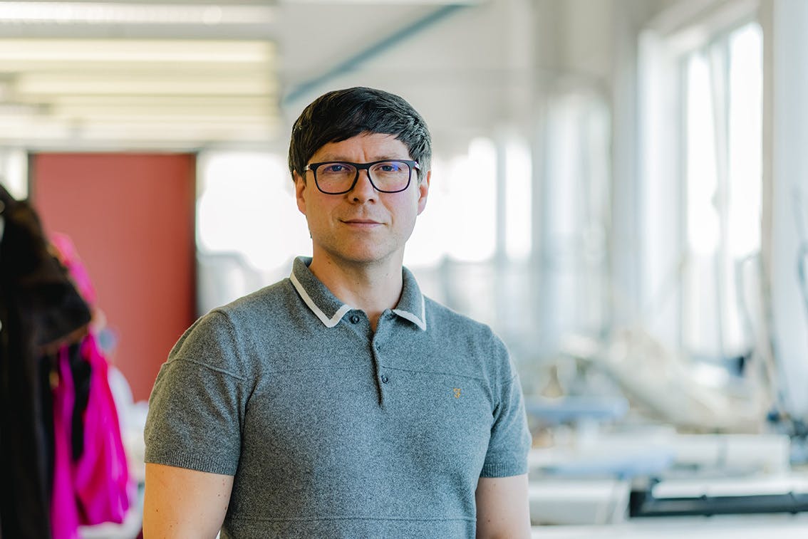 BA Hons Photography Senior Lecturer and Subject Leader Gabriel Van Ingen stands in a light filled studio wearing a short sleeved tshirt at Arts University Plymouth